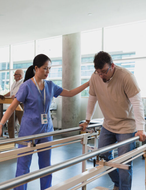 Male and female physical therapists help patients work on various pieces of equipment.